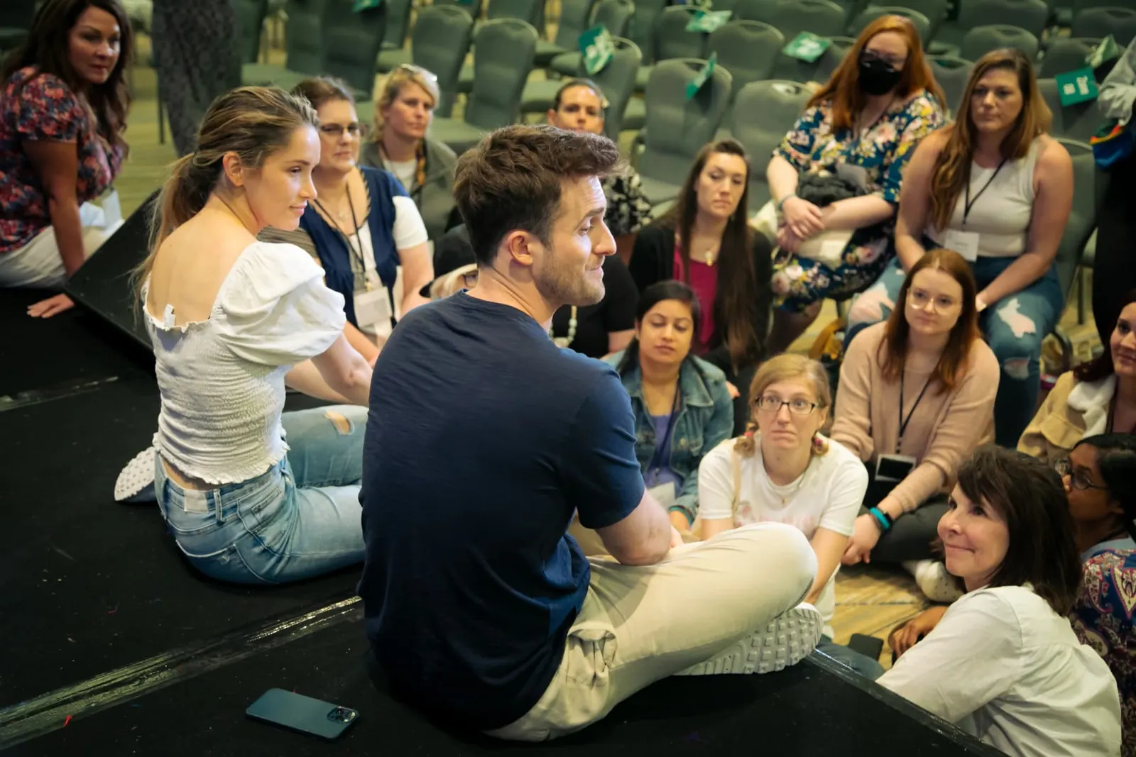 Matthew Hussey sitting on the floor answering questions in a circle of attendees